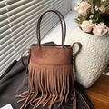Bruine suède bucket bag met lange franjes en rond handvat in een vintage lifestyle setting - Bruin