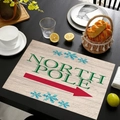 Gros plan d'un set de table en lin avec motif Pôle Nord et flocons sur table noire - Style Flèche du Pôle Nord