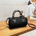 Chic black plush cylinder handbag with leather handles on a minimalist wooden table - Black
