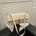 Minimalist beige underarm bag with gold metal buckle on a classic book backdrop - White