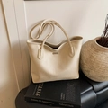 Minimalist beige pebble leather tote bag on art book with elegant lifestyle decor - White