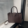 Deep brown pebble leather tote bag with top handles and adjustable strap in soft window light - Brown