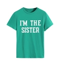 Gros plan sur l'imprimé I'M THE SISTER sur un t-shirt vert en coton col rond - Vert Foncé (Police Blanche)