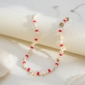 Detalle macro de cadena de cuentas estilo océano con conchas y dijes de estrella - Rojo