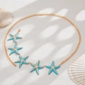 Sexy golden body chain featuring five light blue starfish pendants on white sand - Gold + Blue