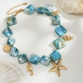 Macro shot of ocean style shell necklace with golden starfish and seahorse charms - Gold + Blue Sea Creature Charm Style (06675)
