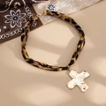 Detail eines Leoparden-Chokers mit goldenem gehämmertem Kreuzanhänger auf beigem Grund - Goldenes Kreuzmodell (07100)