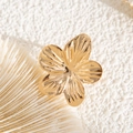 Macro shot of a golden flower earring with radiant texture on a white seashell - Gold Flower Style (03552)
