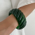 Close-up of a dark green translucent resin bangle with unique vertical stripe texture - Dark Green Spiral