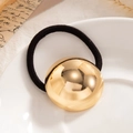 Minimalist elastic hair tie with large polished golden dome metal charm on a ceramic tray - Polished Sphere Gold (0084)