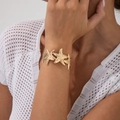Detail of hammered texture on gold starfish bracelet worn with white crochet beach top - Continuous Starfish Style (2872) / Gold