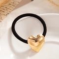 Elastic black hair tie with a minimalist polished golden heart charm on a white plate - Mirror Finish Large Heart Gold (0092)
