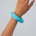 Detail shot of chunky bright blue irregular acrylic bangle on model's wrist - Blue