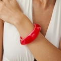 Detail view of a chunky red resin bracelet with marbled textures on a model's wrist - Raspberry Red