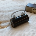 Elegant black cylindrical acrylic clutch featuring a silver lion head handle and gold chain - Black