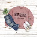 Flat lay of pink crewneck sweatshirt with Wine Tasting slogan and ripped blue jeans - S / Rose Gold (Black Font)