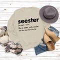Flat lay of sand-colored sweatshirt with 'seester' definition print and autumn accessories - S / Sand (Black Font)