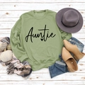 Flat lay of a green crewneck Auntie sweatshirt with casual accessories on a wooden floor - S / Olive Green Sweatshirt (Black Font)