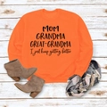 Gros plan du sweat orange avec texte imprimé MOM GRANDMA GREAT et accessoires d'automne - Orange (Police Noire)