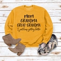 Gros plan du sweat moutarde avec texte MOM GRANDMA GREAT sur fond en bois rustique - Jaune (Police Noire)