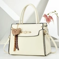 Detailed macro view of cream leather handbag featuring gold clasp and brown bear charm - Off White