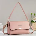 Detailed shot of pink pebble grain leather crossbody bag with silver buckle and branding - Pink
