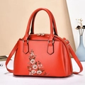 Detailansicht der Blumenstickerei auf roter Trapez-Handtasche mit goldener Hardware - Rot
