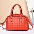Detail of structured shell handbag with grid texture and gold hardware on beige background - Red