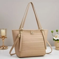 Detail of beige quilted tote bag with pebbled texture and metal logo in a soft setting - Apricot