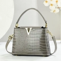 Detail of grey crocodile pattern handbag with gold V-shaped logo and metallic hardware - Gray