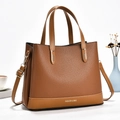 Detail of brown lychee grain leather tote bag showing leaf-shaped ornaments and strap - Earthy Yellow