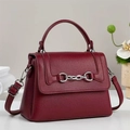 Close-up of burgundy lychee grain leather crossbody bag with silver horsebit hardware detail - Burgundy