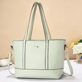 Detail of mint green tote bag featuring golden logo plate and adjustable shoulder straps - Green