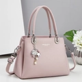 Detailed view of pink lychee leather handbag with silver hardware and pearl charm - Pink