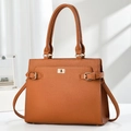Brown litchi grain leather tote bag with gold turn-lock closure in an elegant room setting - Earthy Yellow