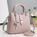 Detail of pink lychee leather handbag featuring silver lock and seashell charm accessory - Pink
