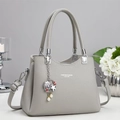 Detail of grey lychee leather handbag featuring a decorative shell and pearl metal charm - Gray