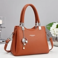 Detalle de bolso de cuero naranja con colgante de estrella y perla y herrajes plateados - Amarillo Tierra