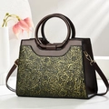 Dettaglio del motivo floreale goffrato vintage sulla borsa a spalla in pelle marrone - Oro