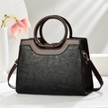 Dettaglio della goffratura floreale su borsa in pelle nera con manici marroni - Nero