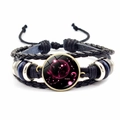 Gros plan d'un bracelet en cuir tressé noir avec breloque en verre du signe du Scorpion - Scorpion