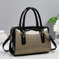 Detailed close-up of woven texture and glossy black leather on a Boston handbag - Khaki