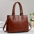 Detail of retro brown PU leather tote bag with gold rivets and adjustable shoulder strap - Earthy Yellow