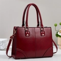 Dettaglio di una borsa bordeaux con finiture dorate e cuciture eleganti in rilievo - Borgogna