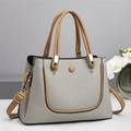 Detail of color-block tote bag featuring grey and brown pebble leather with gold hardware - Gray