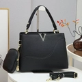 Black pebble leather handbag with V-logo and round coin purse on a display stand - Black