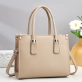Detalle de bolso beige con textura de cuero lichi y herrajes plateados en un entorno - Caqui