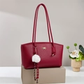 Vintage burgundy leather tote bag with gold bow logo and plush charm on display stand - Burgundy