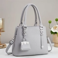 Close-up of grey pebble leather tote bag with silver hardware and mini charm - Gray