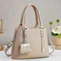 Detailed view of beige pebble leather tote bag with silver hardware and mini bag charm - Light Khaki